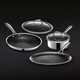 Stainless steel cookware set with pans, saucepan, and glass lids on dark background